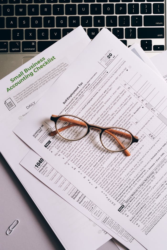 why-choose-us Overhead view of tax documents and eyeglasses on a laptop keyboard, ideal for finance or accounting themes.